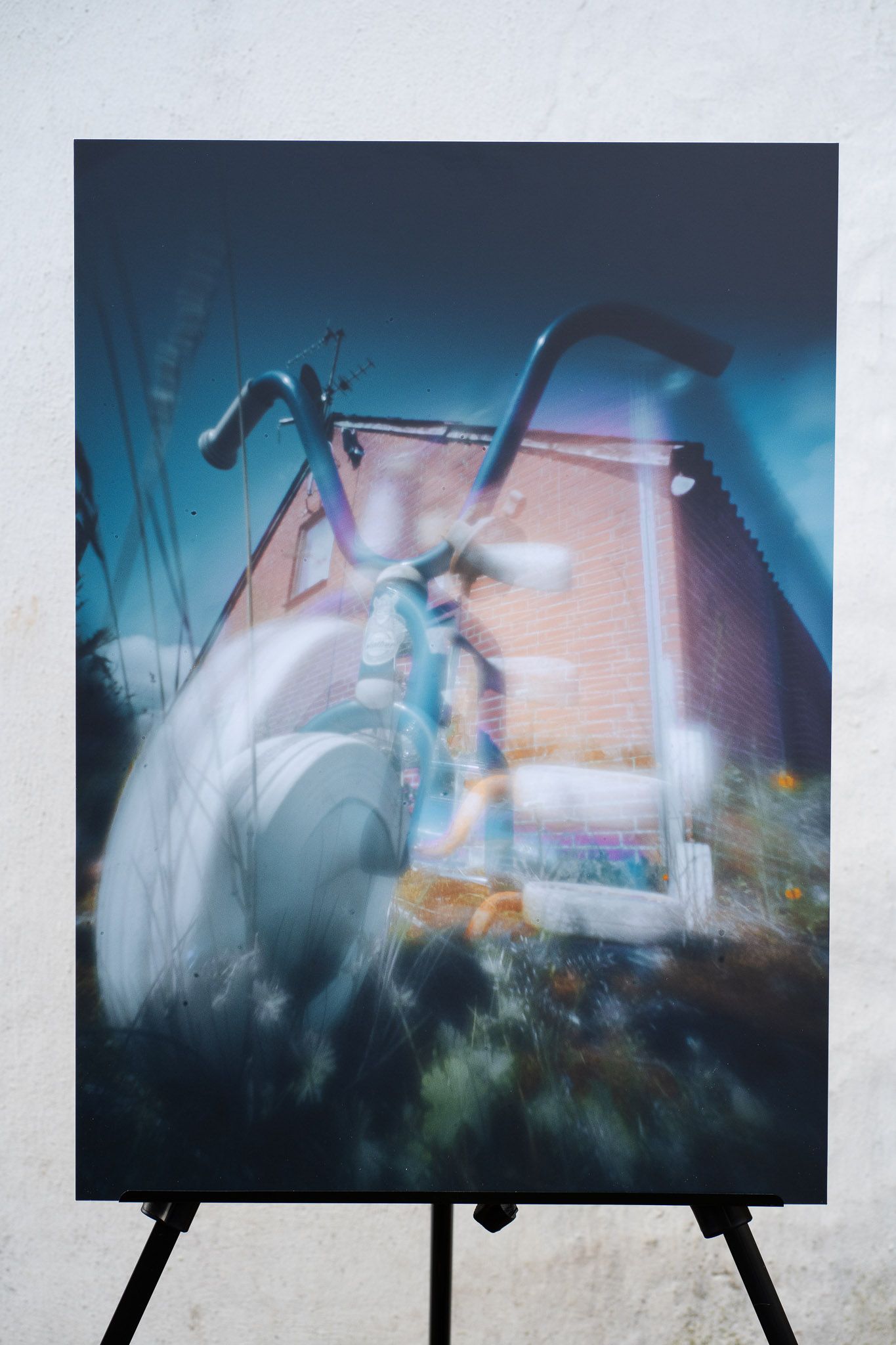 Fotokunst visende en trehjulet cykel foran en bygning