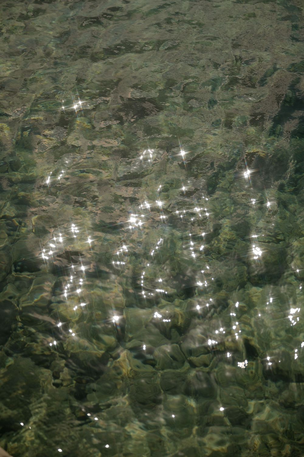 Aerial view of sunlight reflecting off scattered buildings and structures across a green landscape.