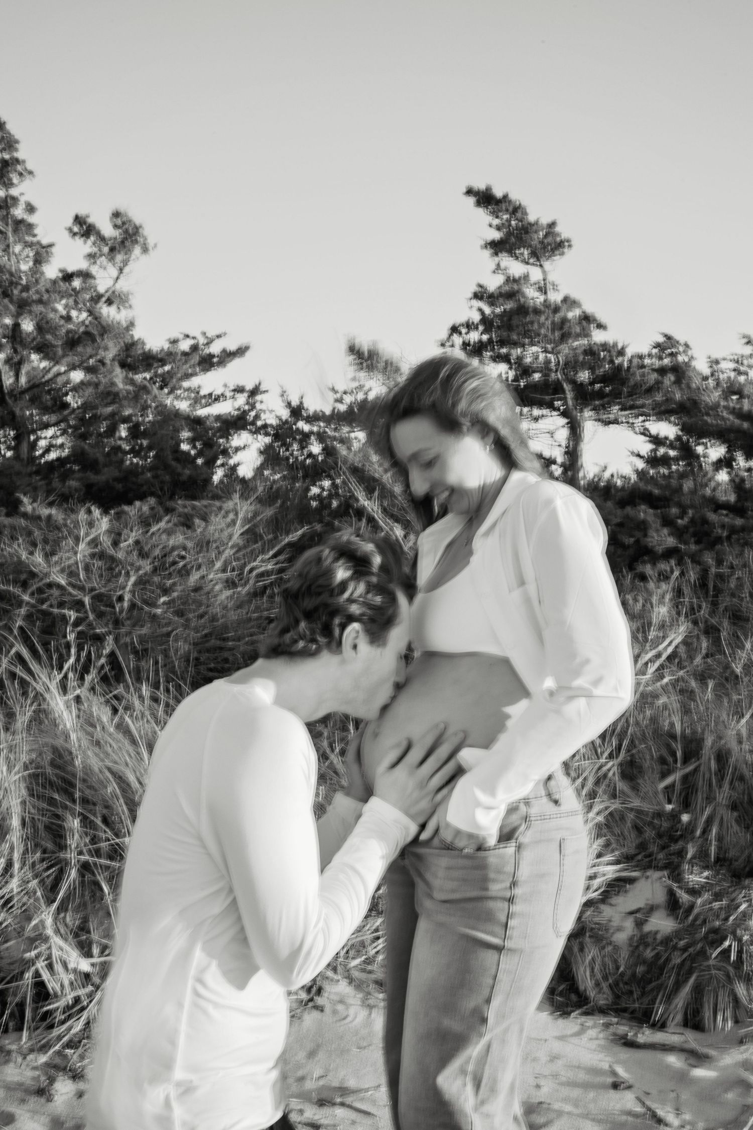 A romantic proposal scene set between rows of grapevines in a scenic vineyard with white flowers and a blanket.