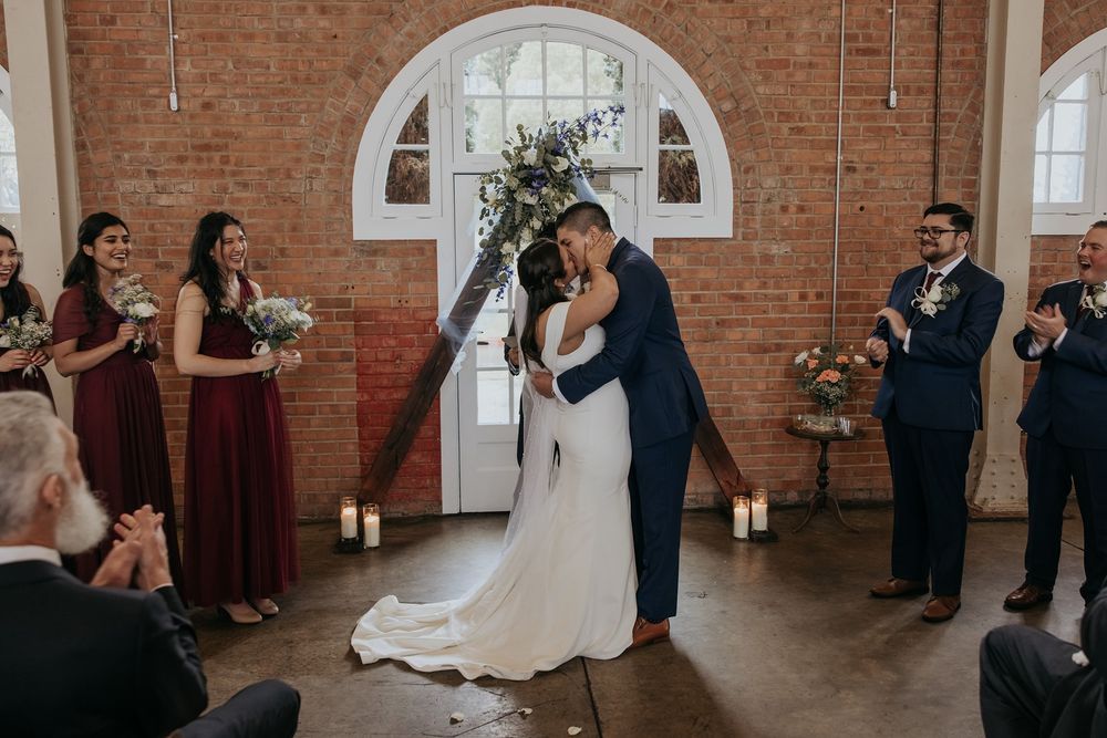 A wedding ceremony sequence showing intimate moments between a couple in a rustic brick-walled venue with arched windows.