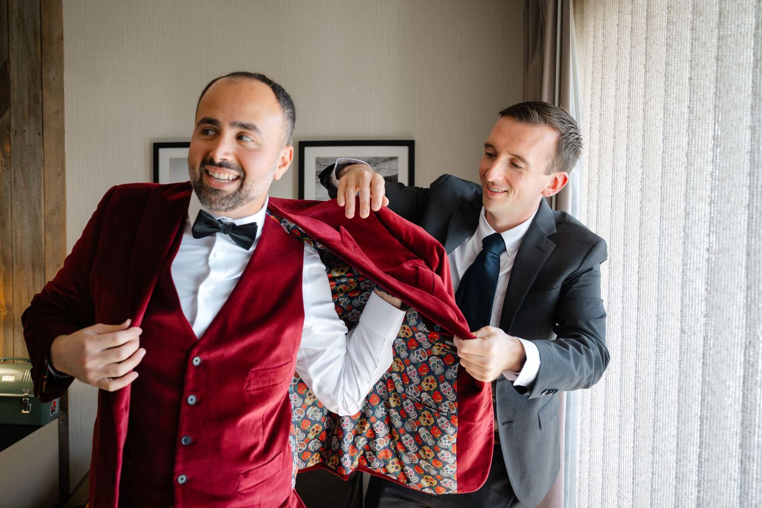 A person in a navy suit adjusts their tie while getting ready for a formal event.