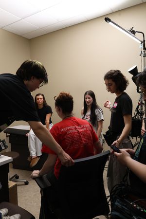Students collaborate in a recording studio setting with microphones and equipment visible in the background.