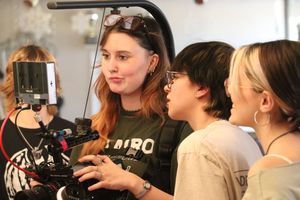 A group of people gather in a crowded indoor space looking at something off camera.