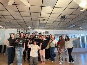 A group of people dancing and practicing choreography together in a bright studio with mirrored walls.