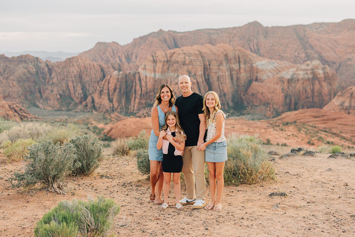 Family of four posing together in front of stunning red rock canyon landscape in the American Southwest.