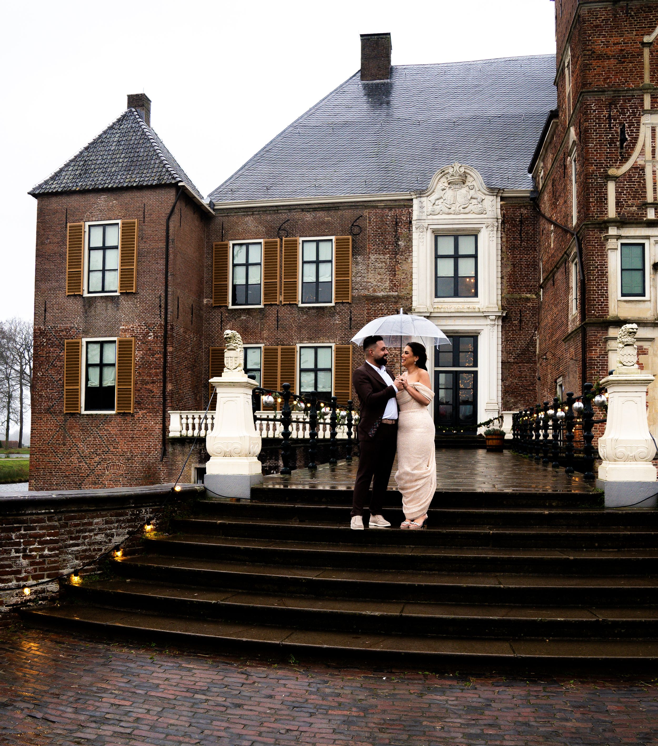 Een elegant paar deelt een paraplu op hun regenachtige trouwdag op de trappen van een historisch Nederlands herenhuis.