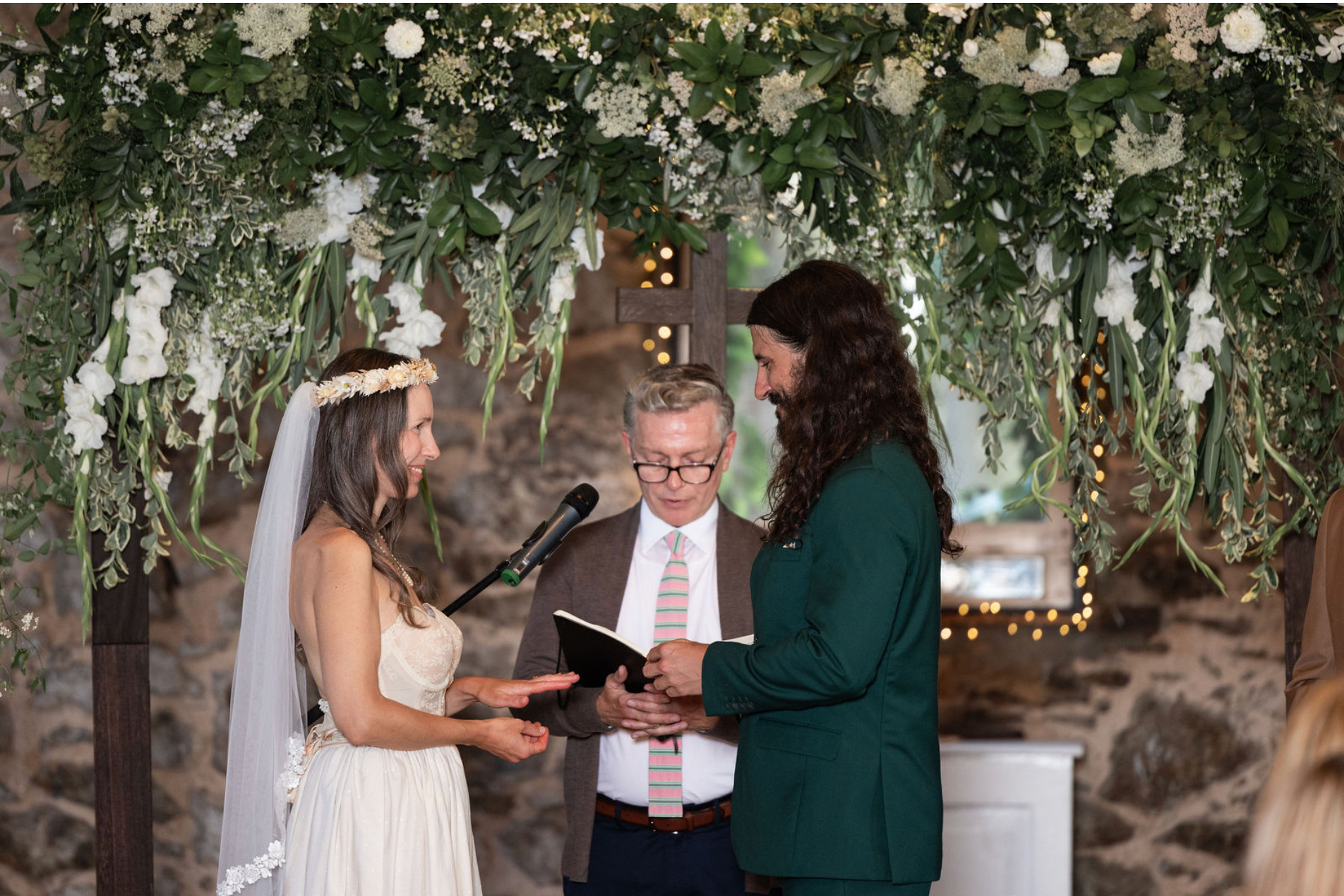 A wedding celebration scene with string lights and greenery decorations in an outdoor venue setting.