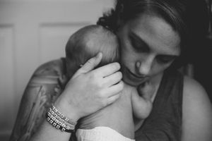 Black and white photo of a mother tenderly holding her newborn baby close to her chest.