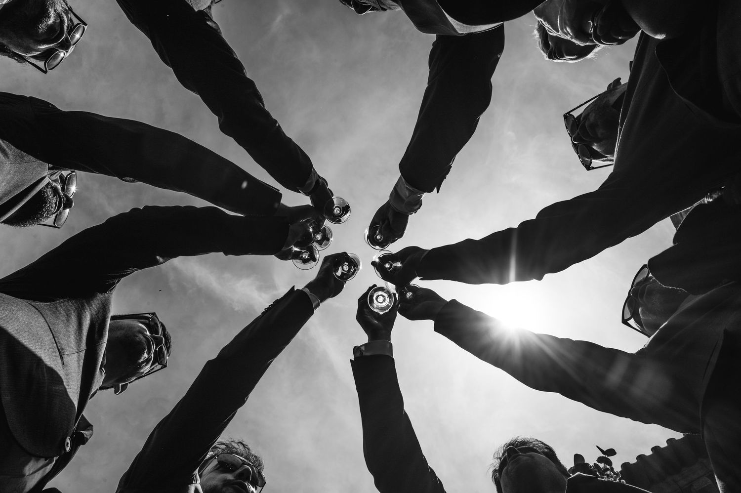A dramatic low angle view looking up at a group of people forming a circle against a cloudy sky background.