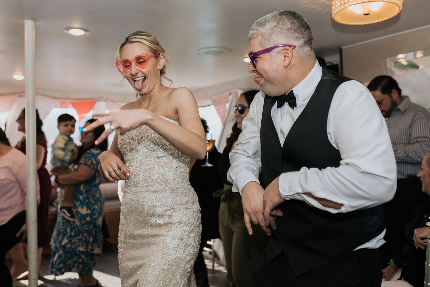 Wedding guests dance and celebrate together during a lively reception party on the dance floor on a boat in San Diego.