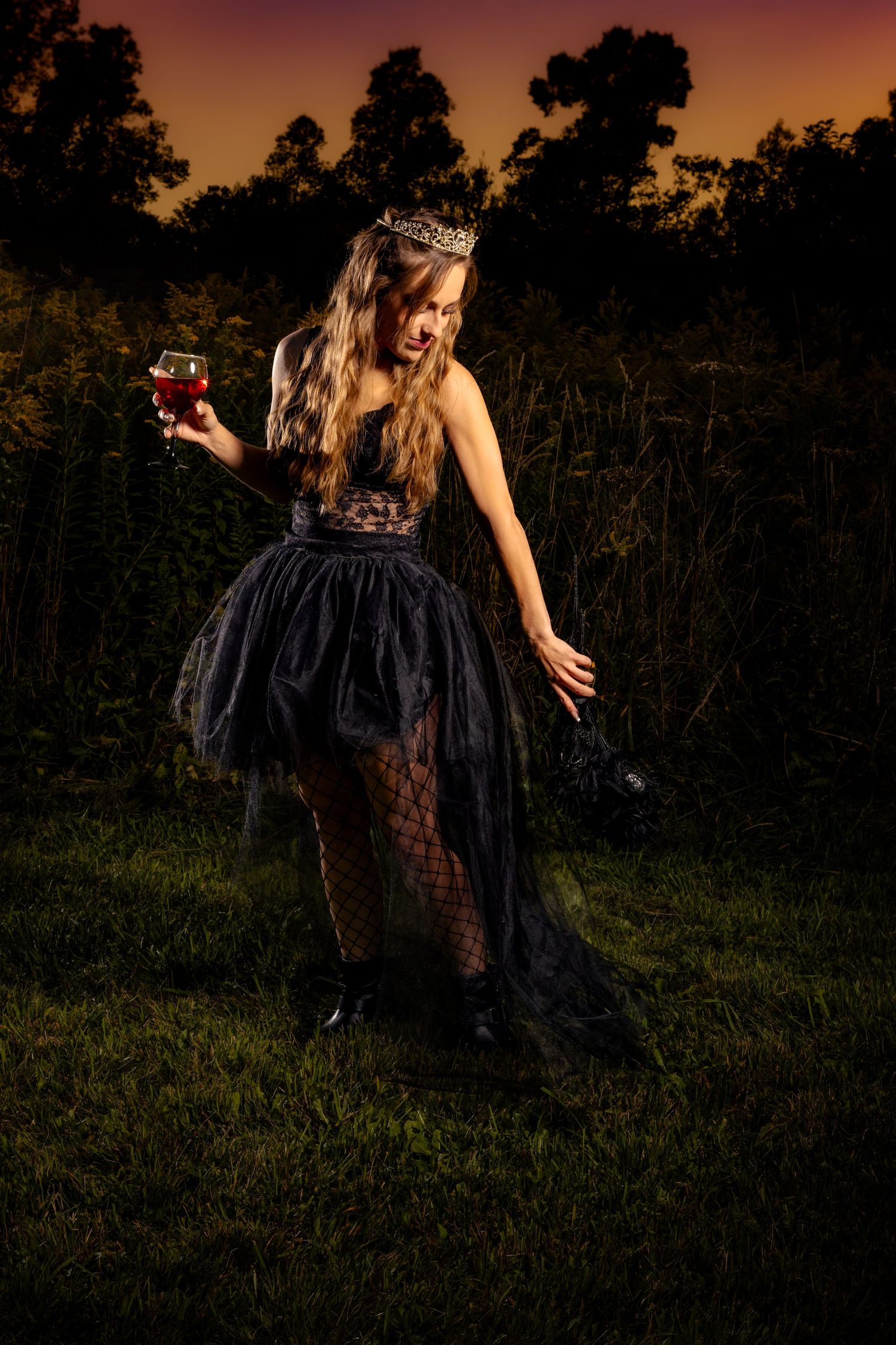 A figure in a flowing black dress dances and twirls in a field at sunset creating a dramatic silhouette against the sky.