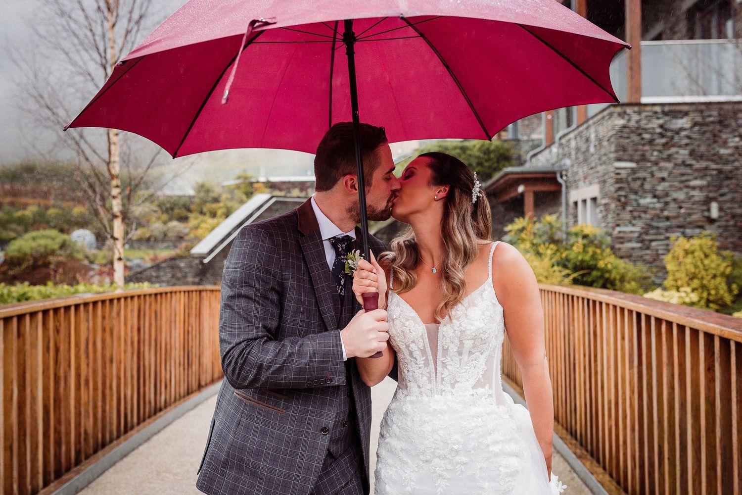 Bride and groom at Lodore Falls on a rainy day with a red umbrella