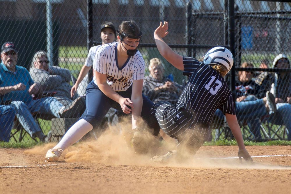 Baseball player slides into home plate creating a cloud of dust during an intense play at the plate.