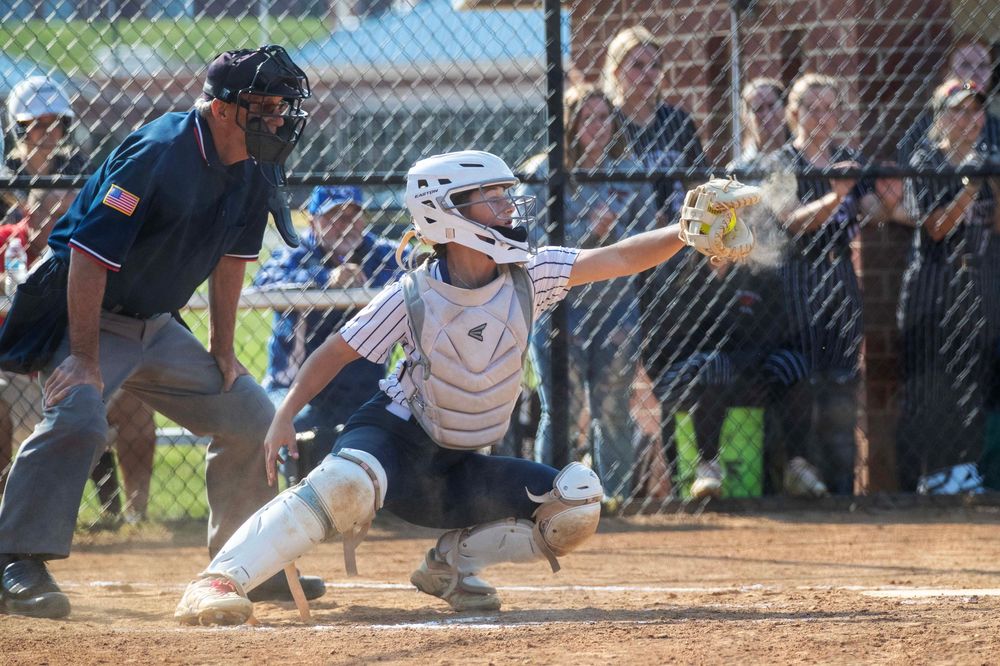 Baseball player slides into home plate during intense game action while catcher attempts to make the tag.