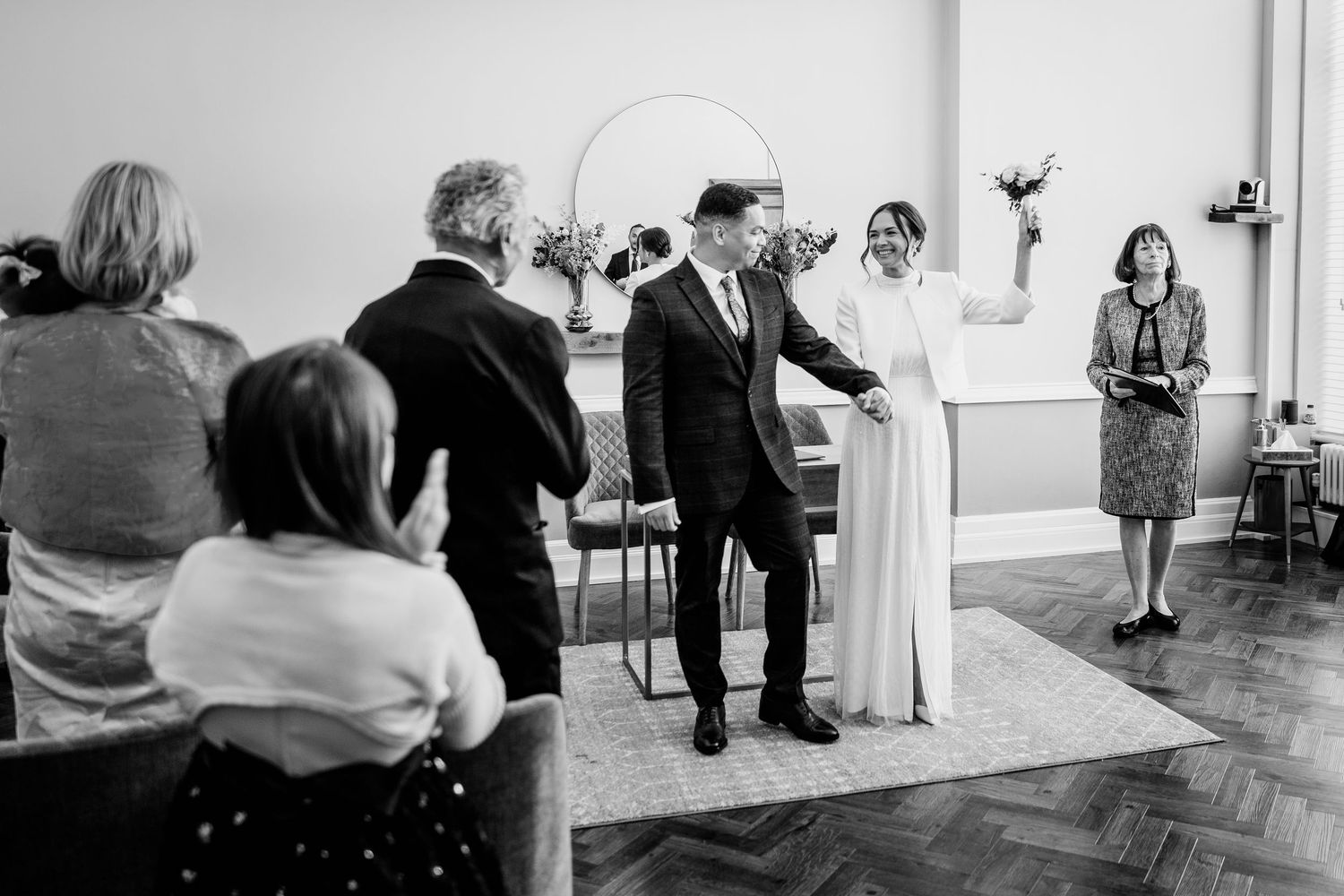 A black and white image showing a formal wedding ceremony with a bride, groom, and guests in attendance.