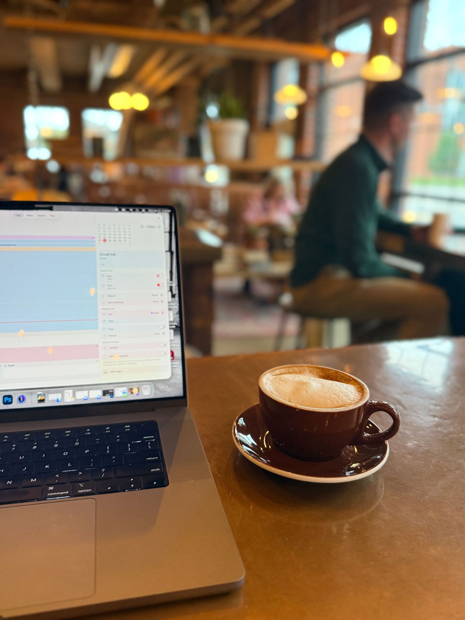 A laptop computer on a wooden table with a cup of coffee in the foreground.