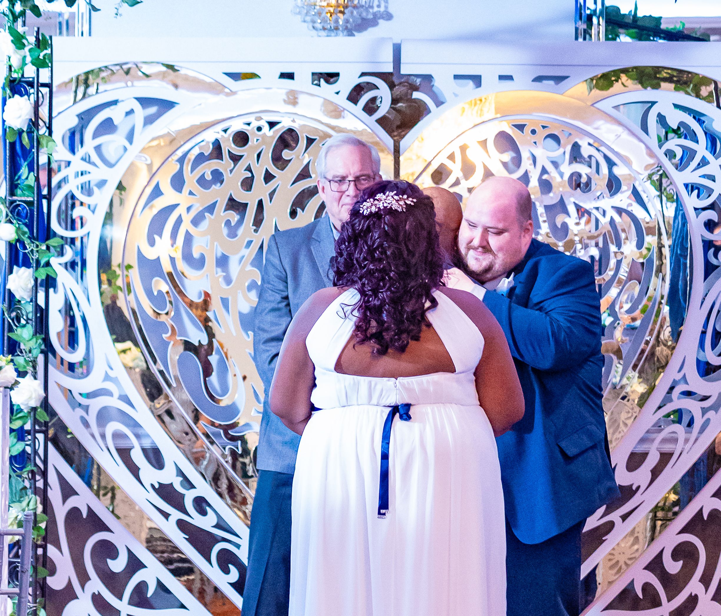 Bride and groom sharing their first kiss under an ornate arch at the ceremony by Zeus Holbrook San Diego Wedding Photographer