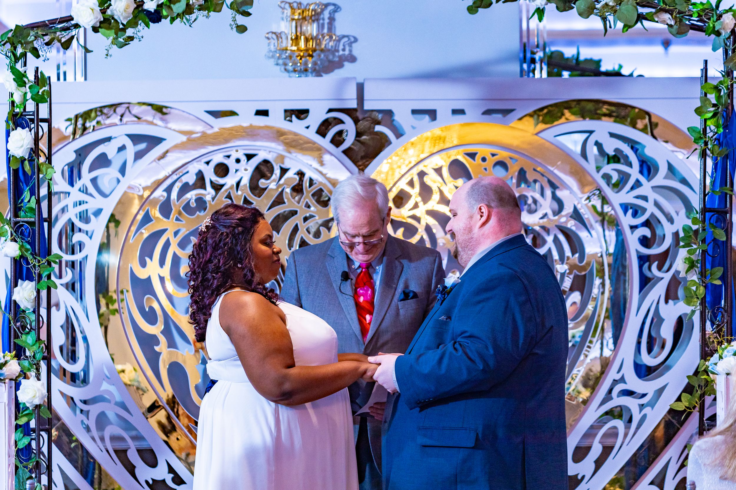 Bride and groom exchanging vows under an ornate decorative arch by Zeus Holbrook San Diego Wedding Photographer