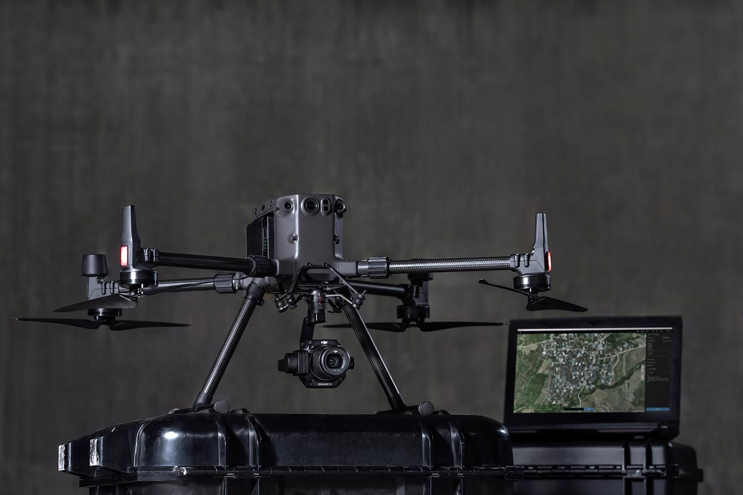 Professional DJI Matrice 300 RTK drone displayed on a case with a monitor showing aerial map footage in a studio.