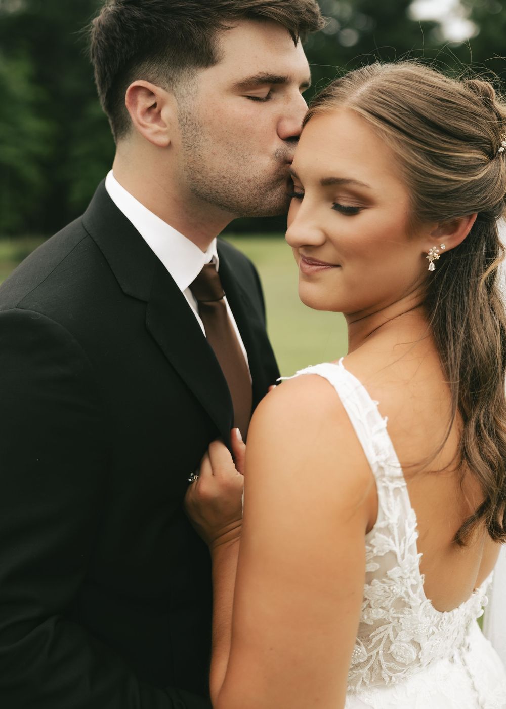 Groom kissing bride on temple during romantic outdoor wedding portrait session.