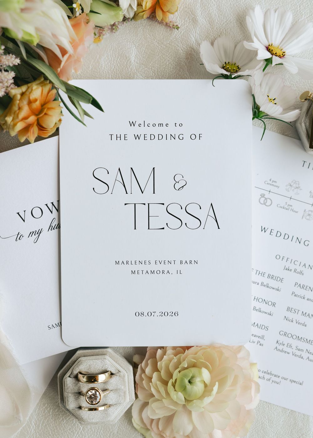 Elegant wedding program for Sam and Tessa at Marlenes Event Barn, Metamora IL, dated 08.07.2020, surrounded by flowers and rings.