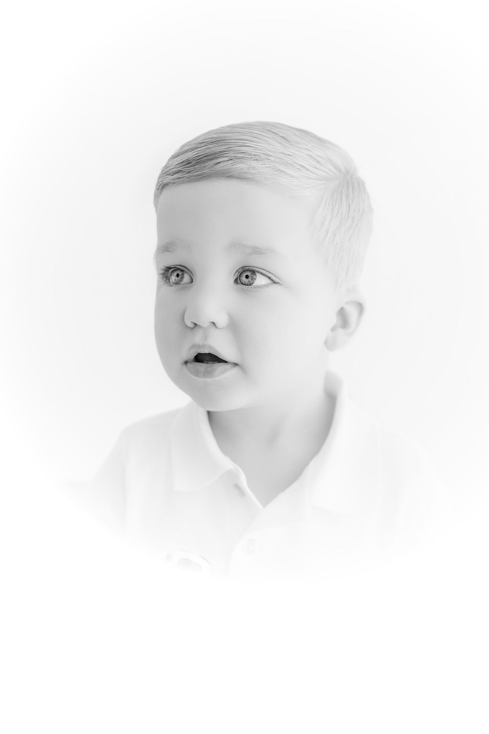 Black and white portrait of a young blonde boy with blue eyes wearing a white shirt.