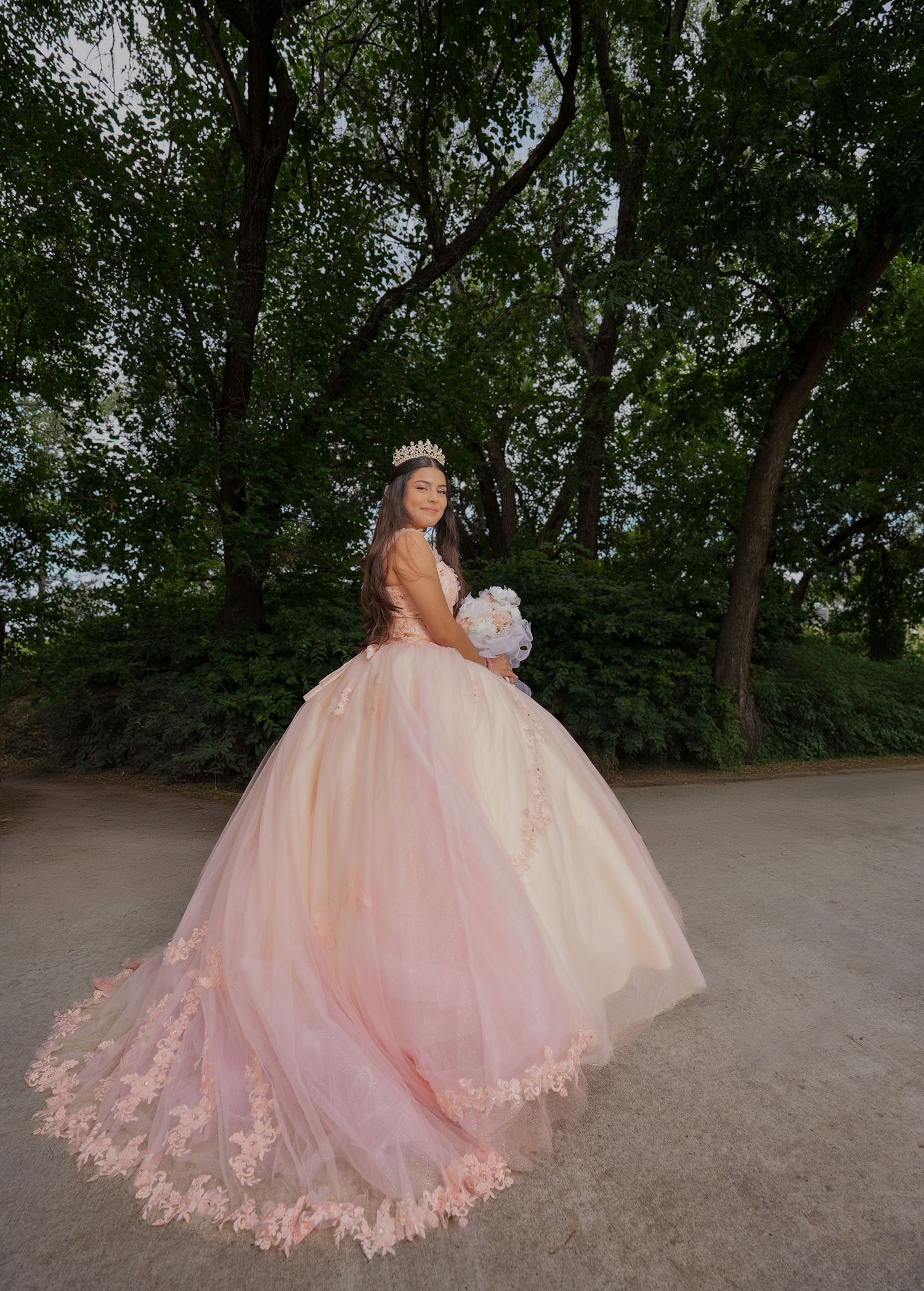 Elegant rose gold ballgown with intricate embroidery photographed on stone steps in warm church lighting.