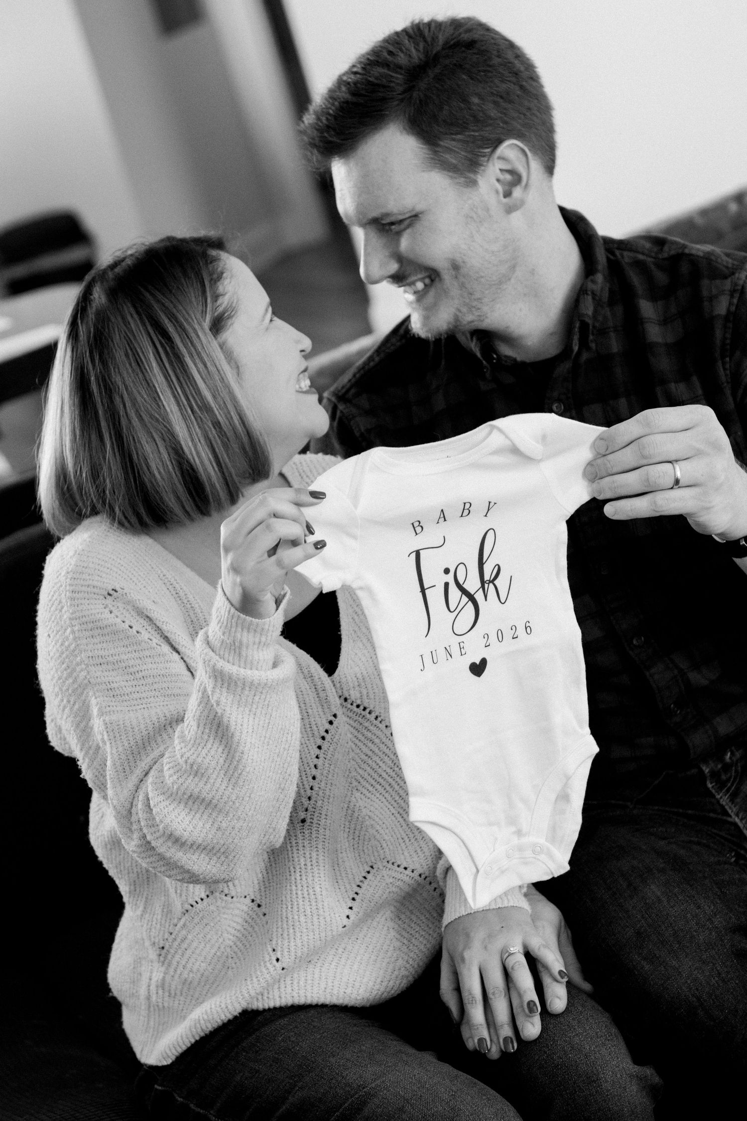 couple holding up onesie