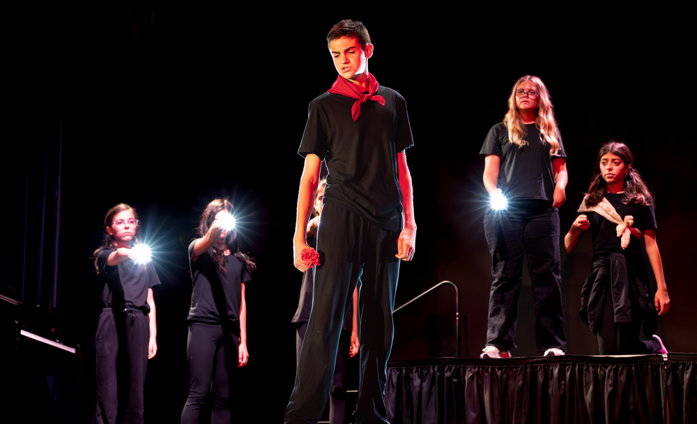 Five student performers in black stand on stage holding flashlights during a dramatic theater production.