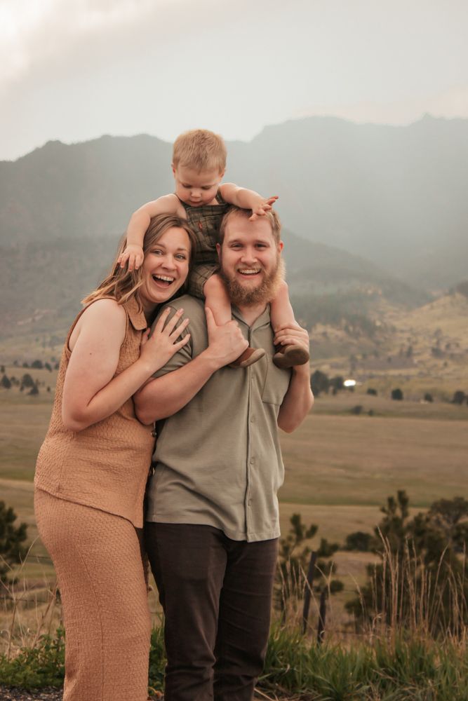 Parent lifting baby up against a beautiful golden sunset backdrop | What to Wear for Family Photos