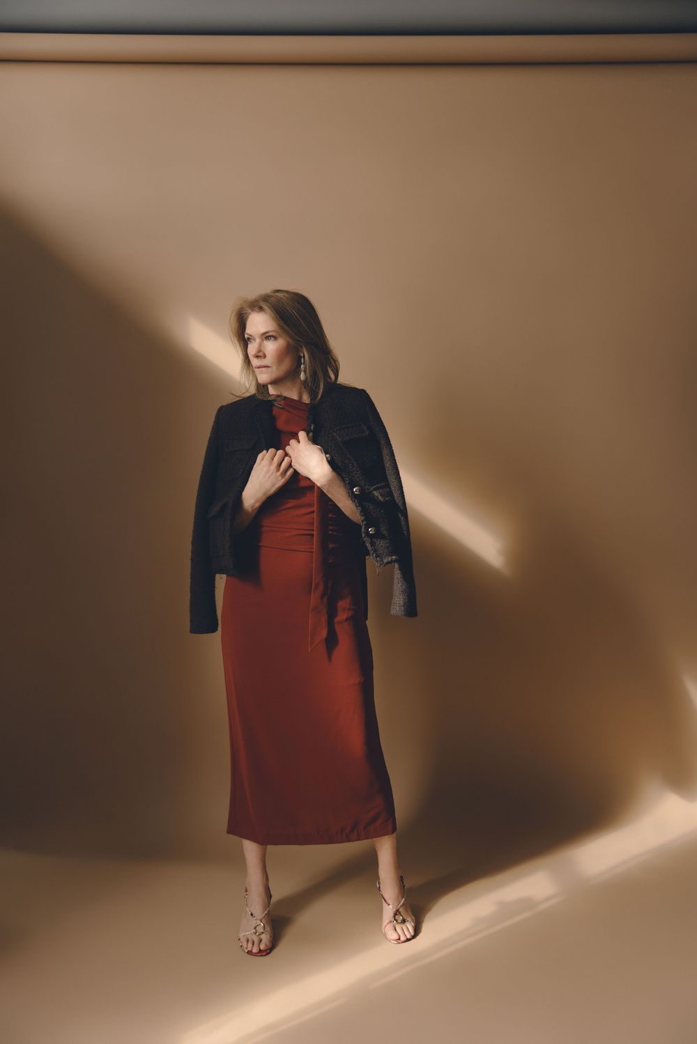 A series of fashion photos showing someone in a red dress and denim jacket against a beige backdrop with dramatic lighting.