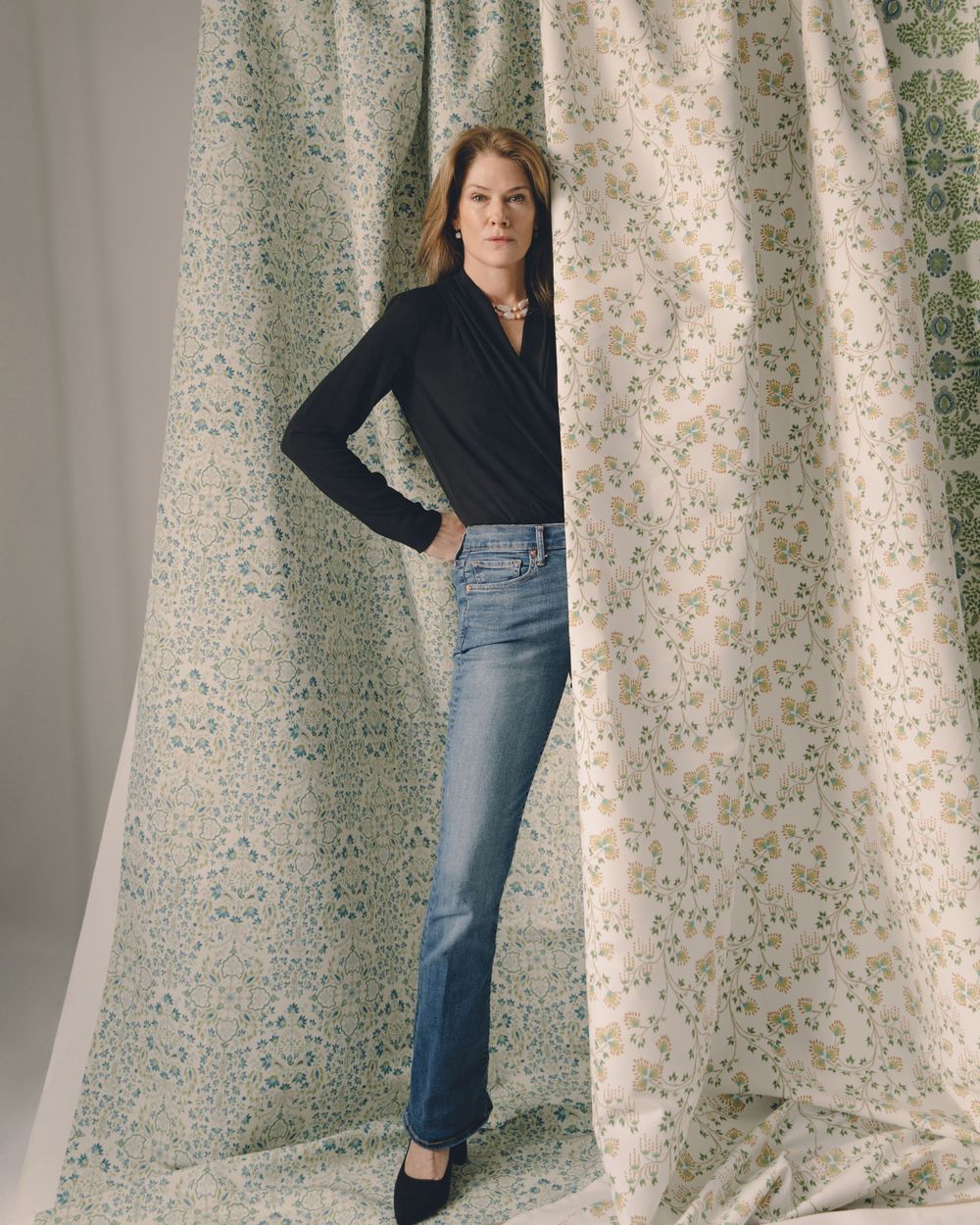 A person poses in a navy sweater and denim skirt against a floral wallpaper background in a series of fashion shots.