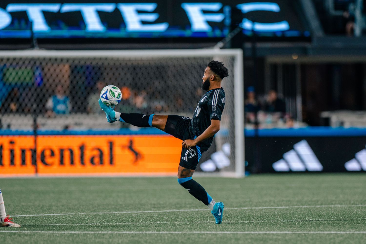 Charlotte FC player performing acrobatic kick during MLS match at home stadium.