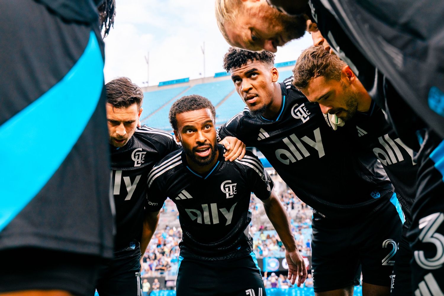 Charlotte FC players huddle in black ally jerseys before MLS match.