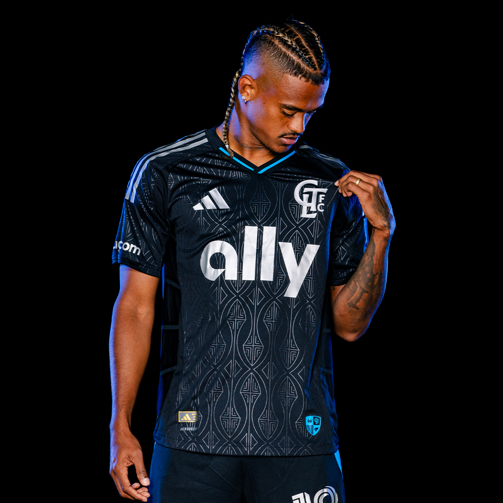 Charlotte FC player wearing black Adidas ally-sponsored jersey posing confidently.