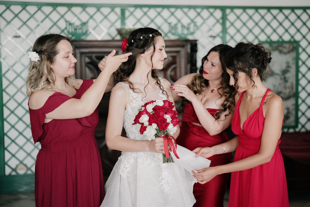 Bride and bridesmaids dressed in red during wedding preparations in Imperia