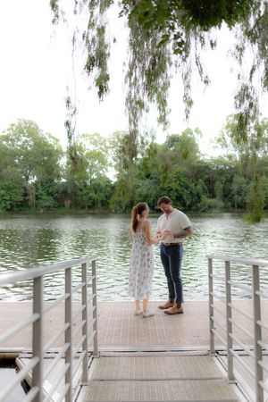 A couple shares a tender moment on a wooden dock overlooking a serene lake.
