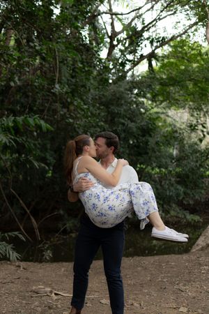 A romantic couple shares a playful dip pose in a secluded wooded setting.