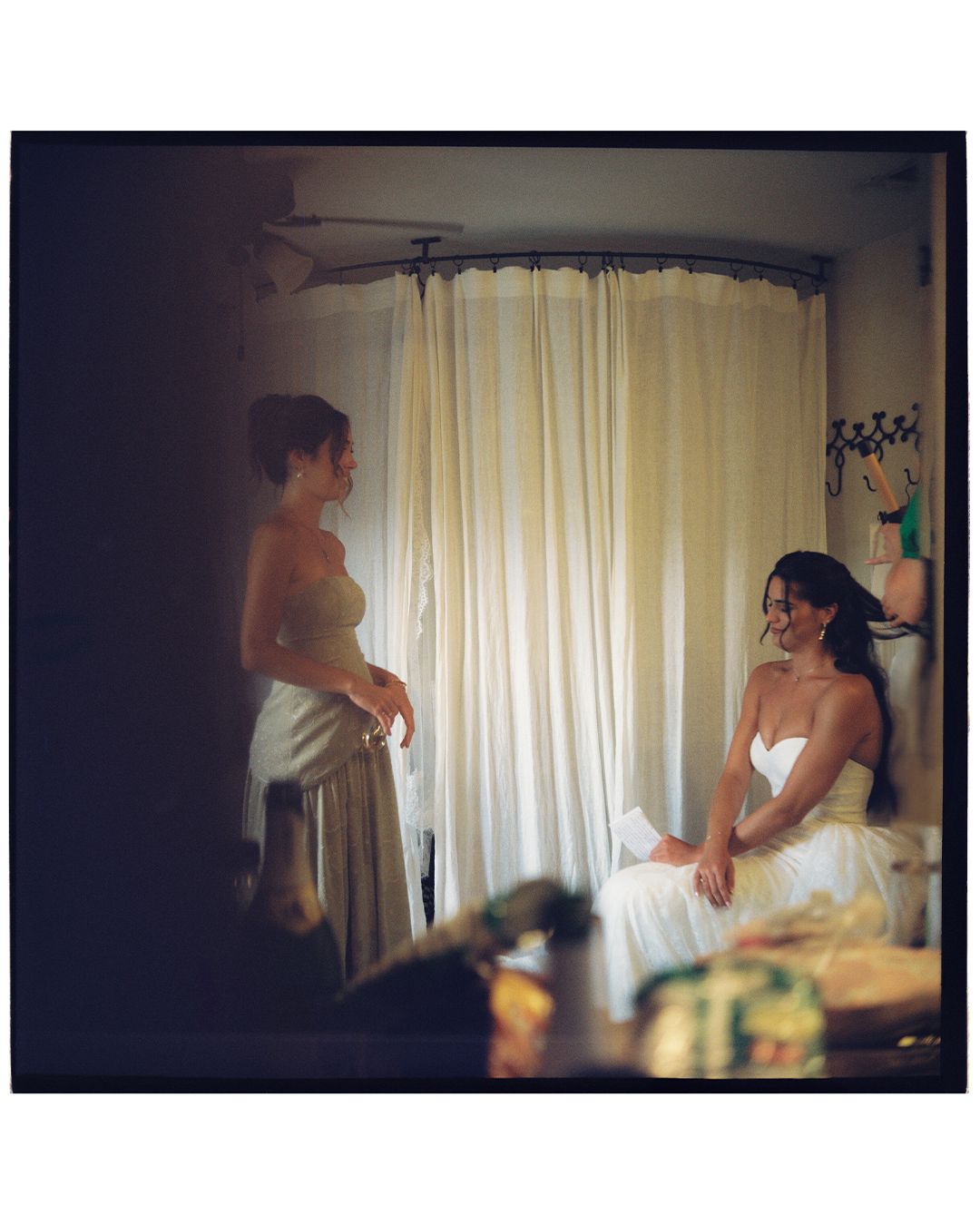 Silhouettes of people preparing in a sunlit room with sheer curtains creating a dreamy atmosphere.