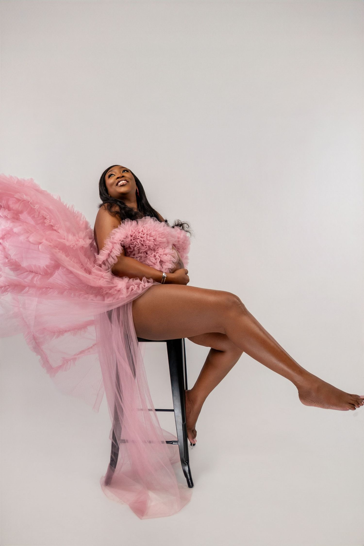 Artistic fashion photo series showing a model in flowing pink tulle fabric posing dramatically on a chair.