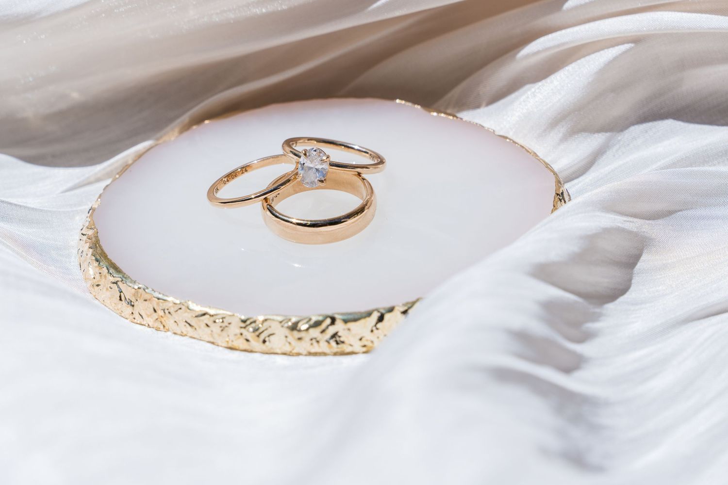 Delicate gold rings with intricate designs arranged in a row on white fabric background.