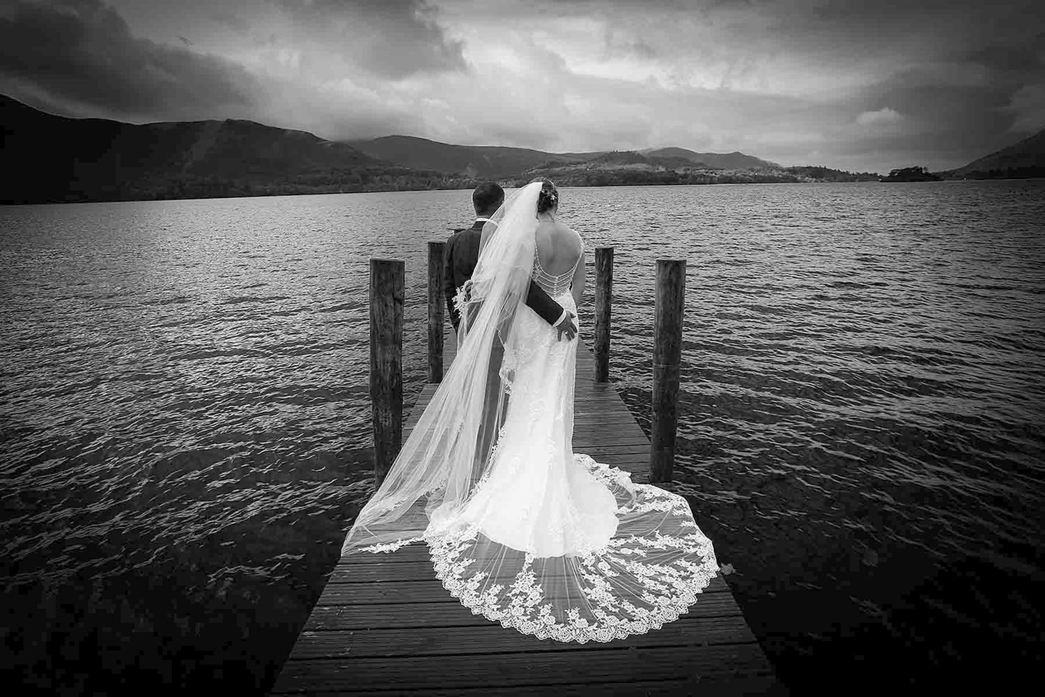 A romantic lakeside wedding photoshoot with dramatic black and white views of a dock over mountain waters.