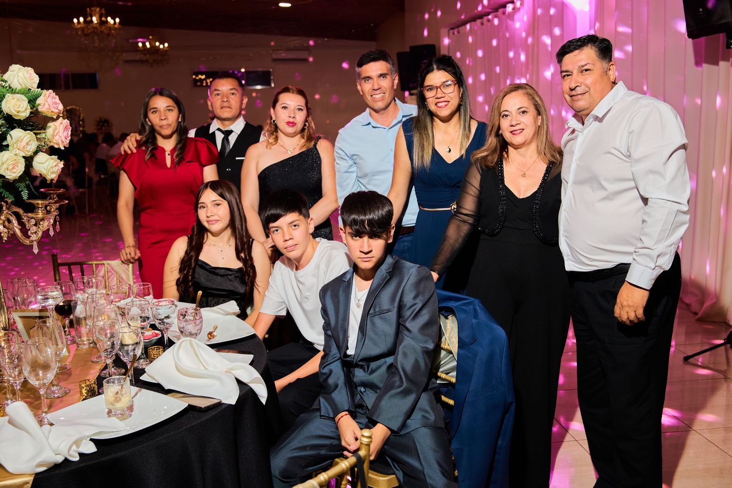 Guests enjoying themselves at an elegant wedding reception with pink lighting and floral decorations.