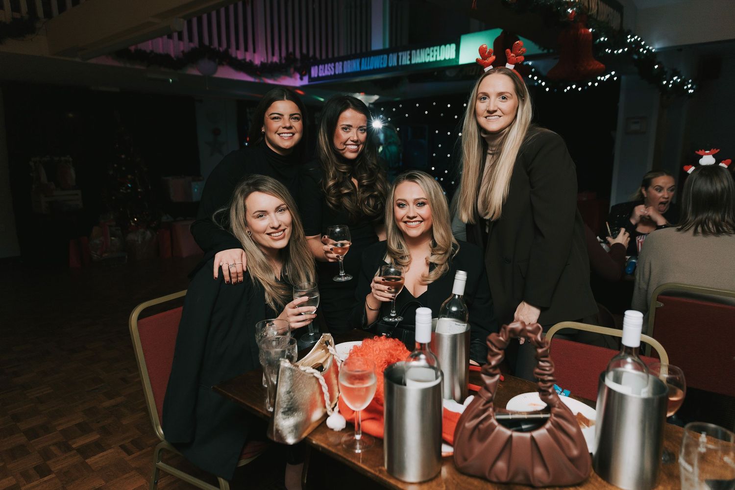 People enjoying drinks and socializing at a dimly lit party venue with festive decorations.