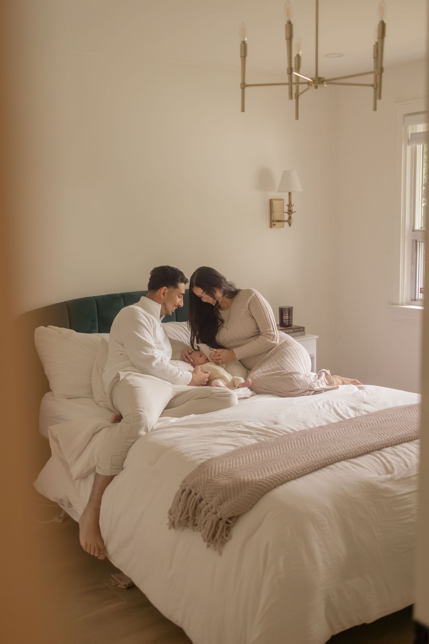 Couple resting together on white bed with beige blanket in minimalist bedroom with natural lighting.