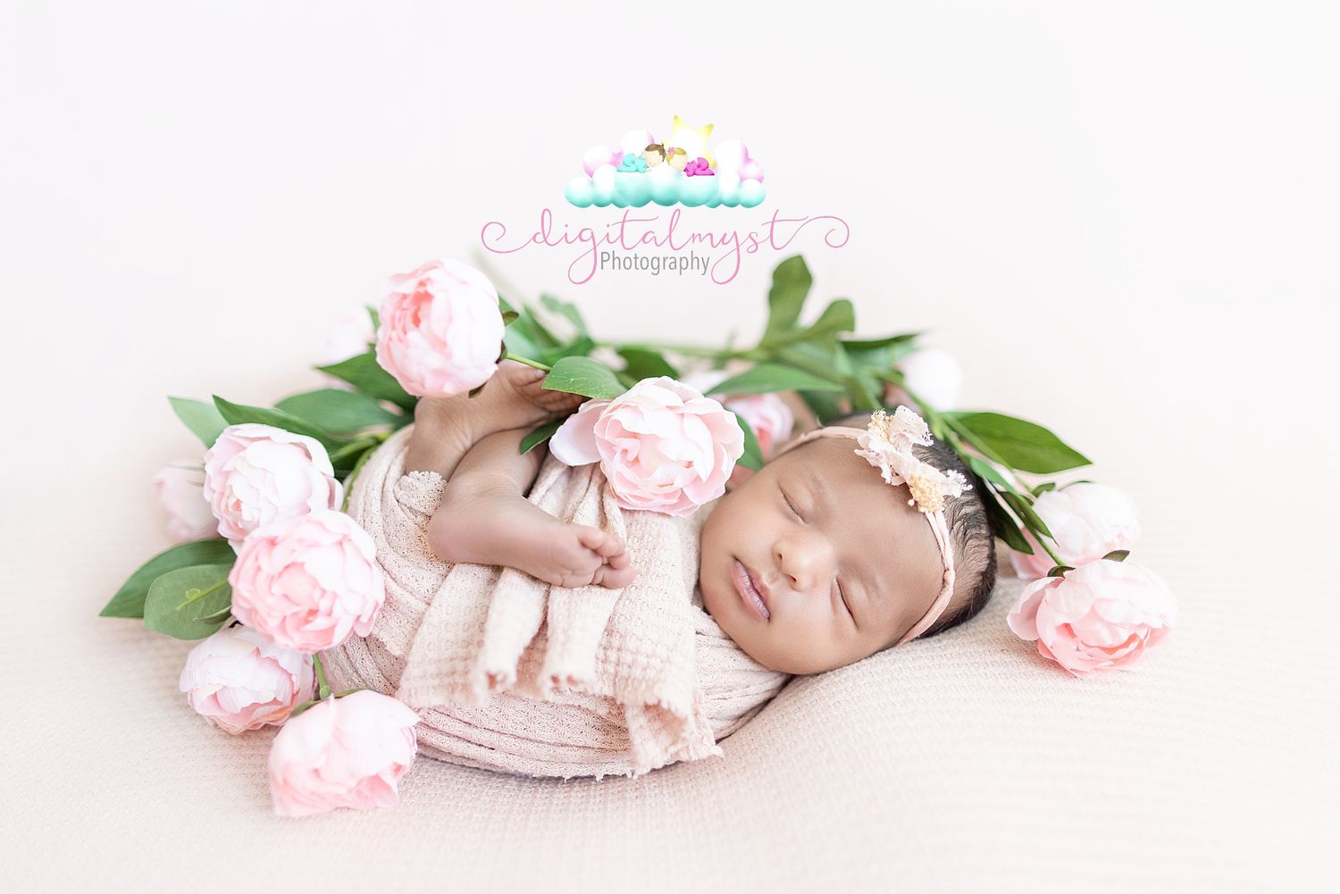 A sleeping newborn baby in white lace outfit lies peacefully among soft pink peonies in a dreamy studio setting.