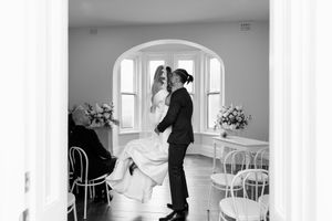 Black and white candid photo of groom lifting bride during a joyful wedding ceremony moment.