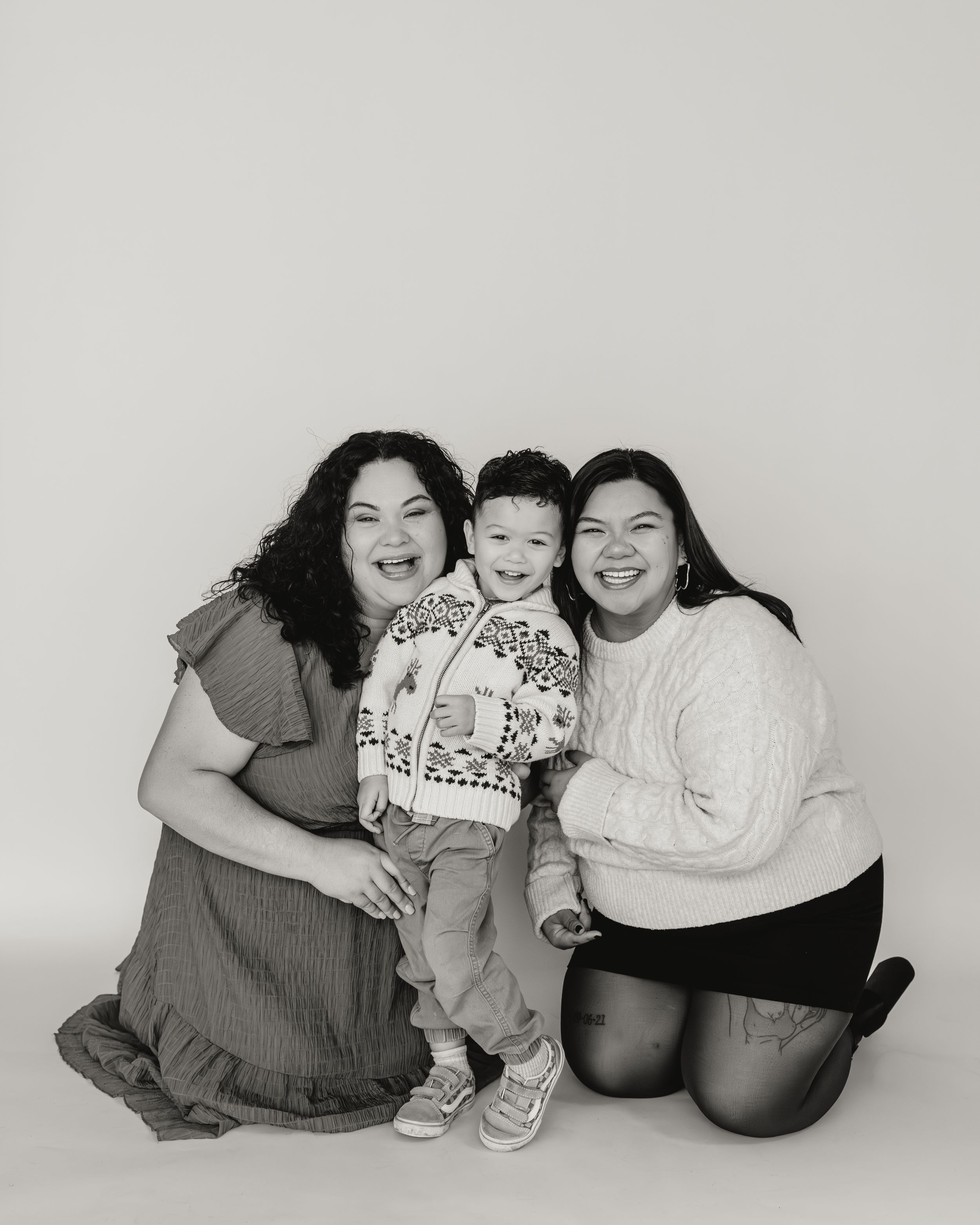 Black and white photo series showing a group sitting together in casual poses on a white background.