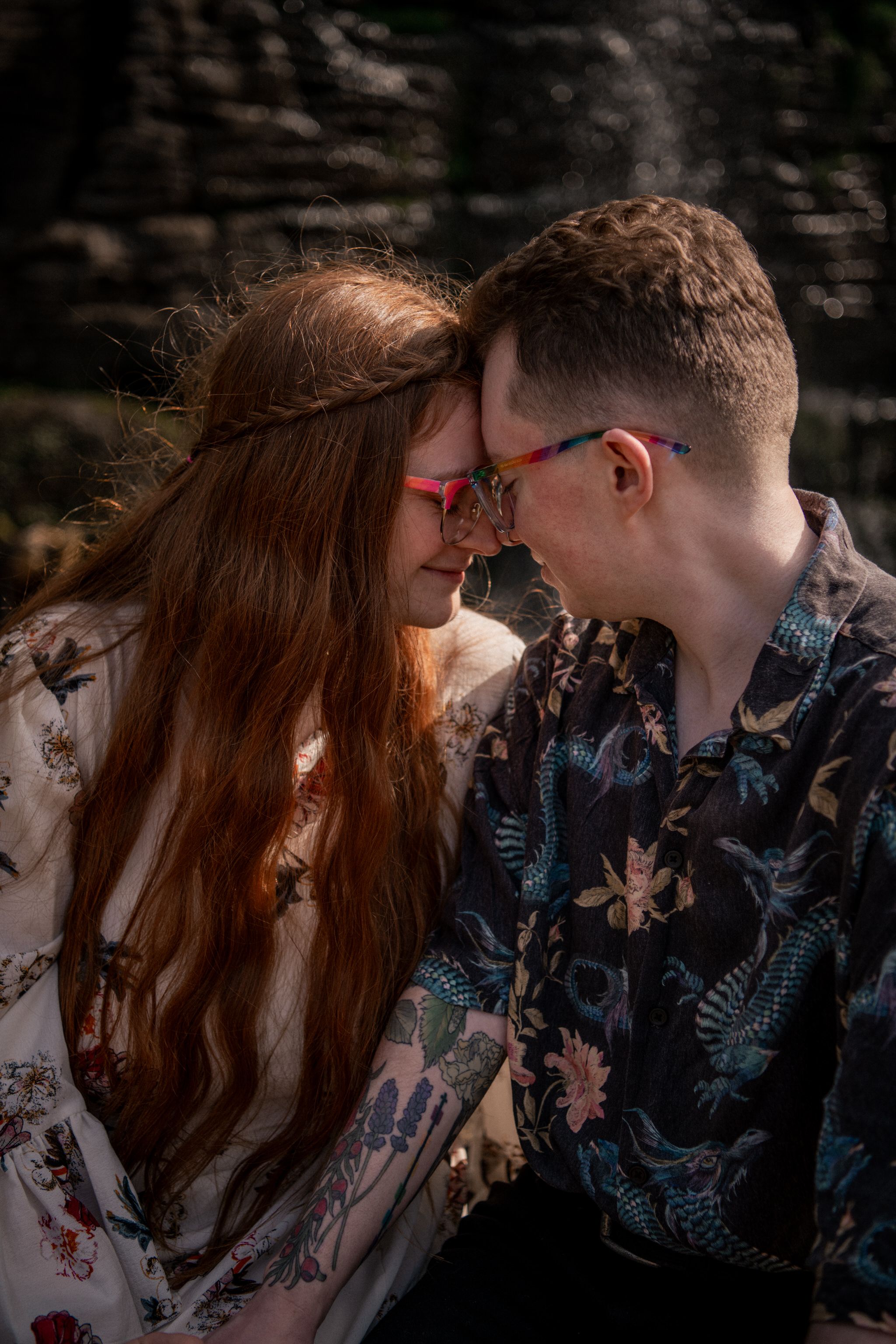 A tender embrace between two people wearing contrasting floral patterns in a moody outdoor setting.