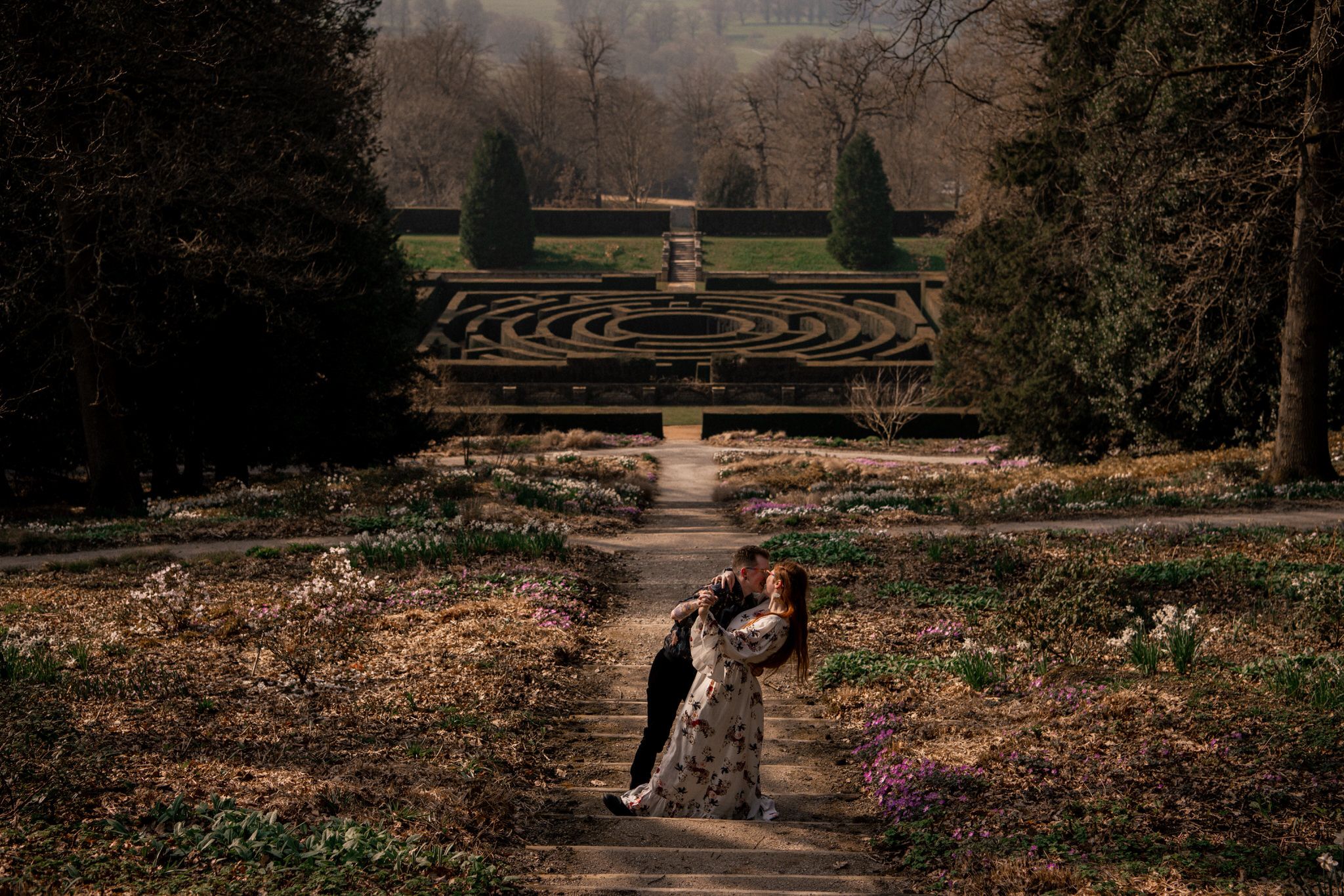 A scenic garden path with ornate landscaping and flowering plants stretches into the distance.